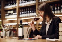 Female wine expert person tasting wine during sommelier degustation sitting at the table being in winery cellar